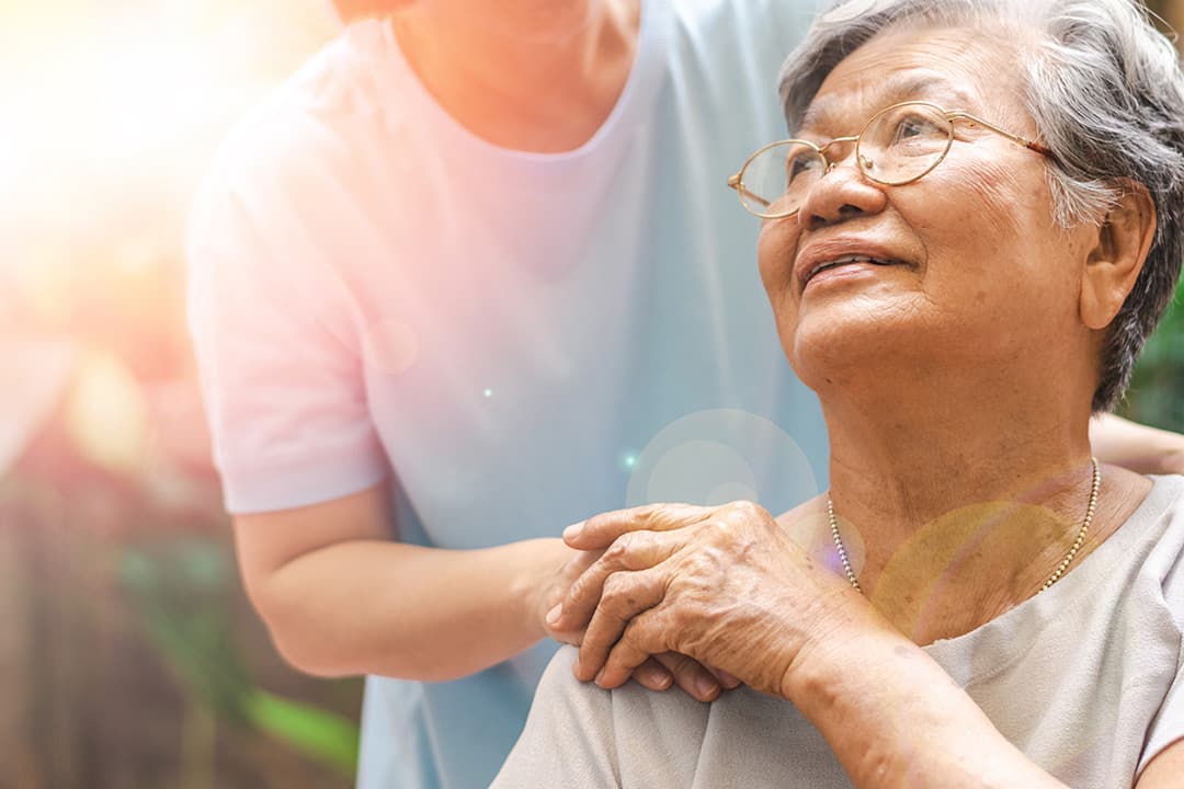 A caregiver holding the hands of an older woman