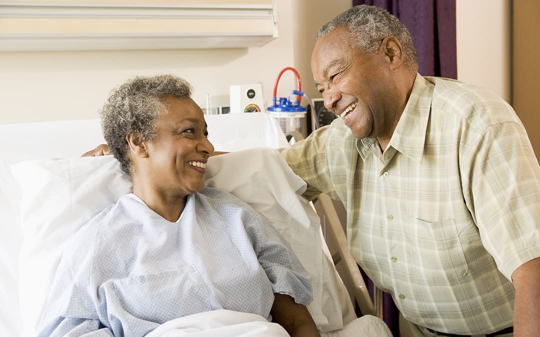 An older couple sitting close together in a hospital room