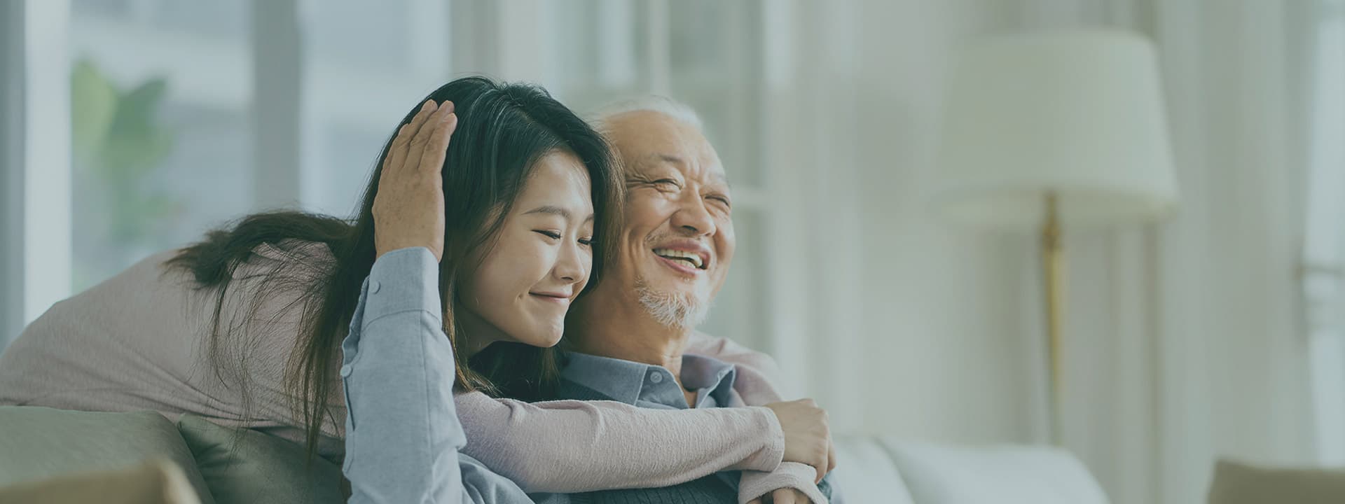 An adult daughter hugging her older father