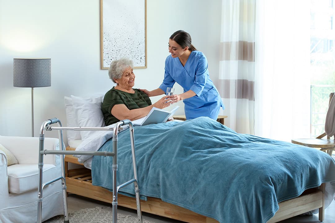 A nurse helping an older woman in her bedroom