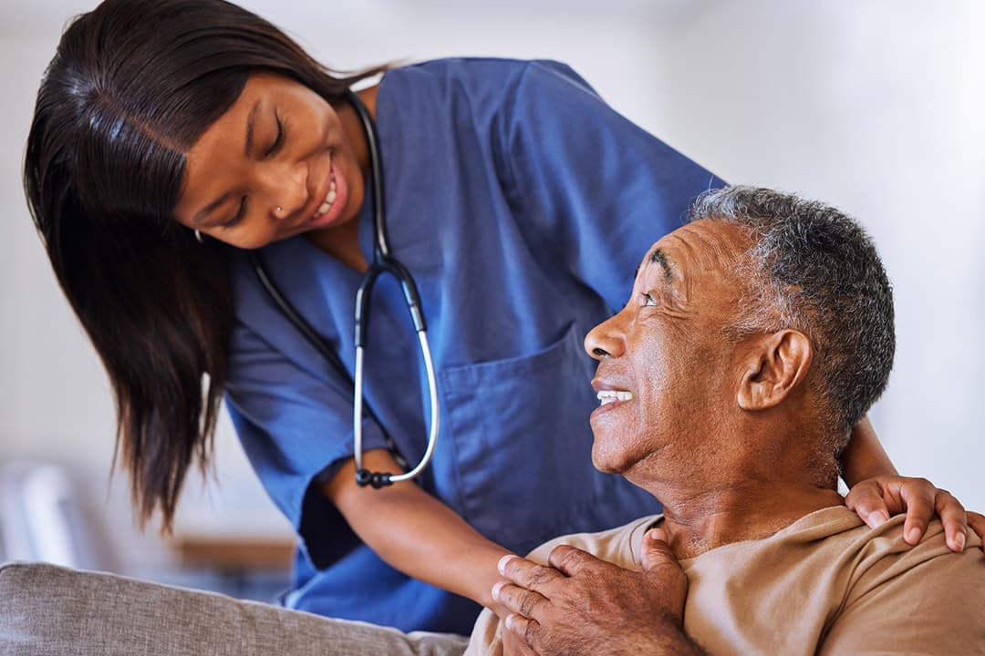 A hospice nurse smiling with an older man at home